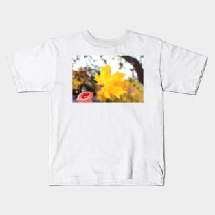 Hand holding golden yellow maple leaf Kids T-Shirt